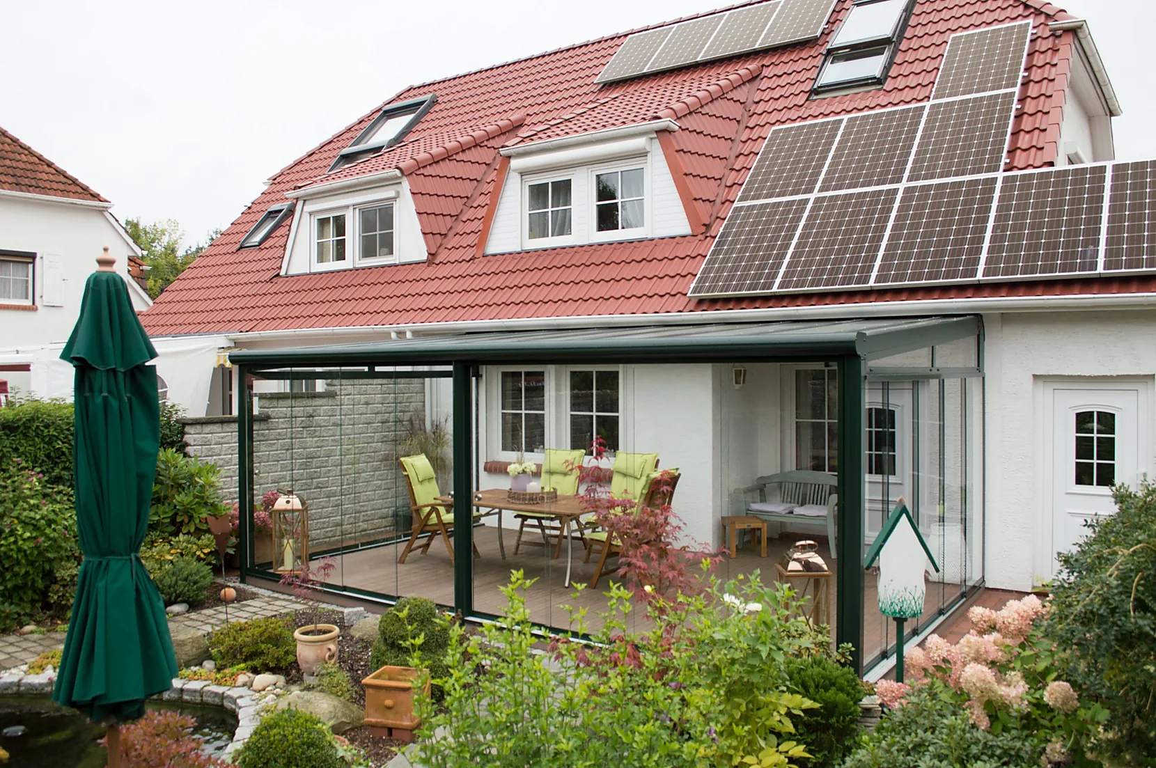 Verglaster Terrassenbereich als Verbindung von Wohnhaus und Garten unter einer transparenten Überdachung