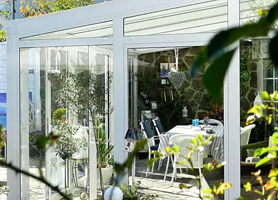 Heller verglaster Terrassenraum mit weißen Profilen und viel Tageslicht